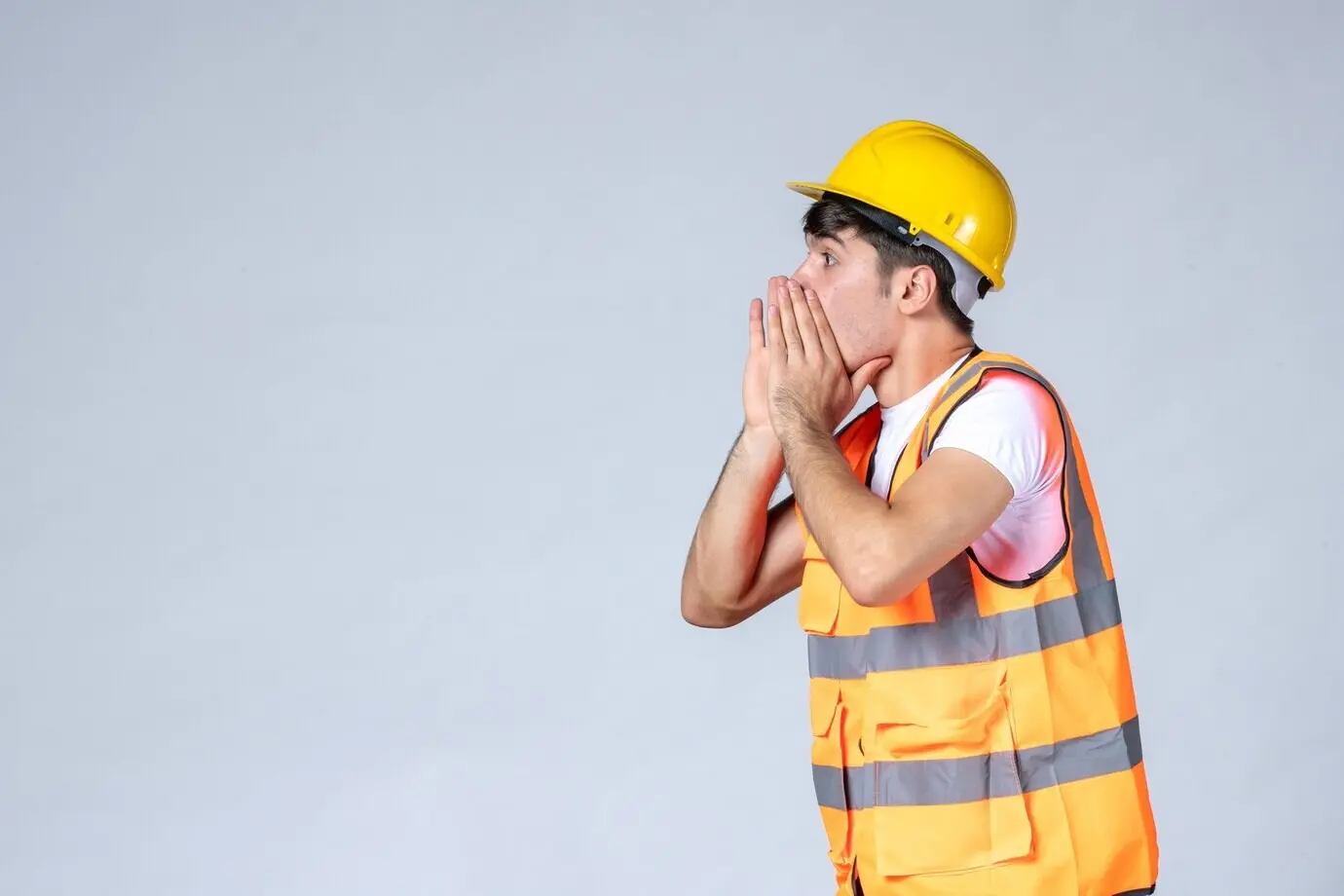 Frontalansicht eines männlichen Bauarbeiters in Uniform vor weißer Wand.